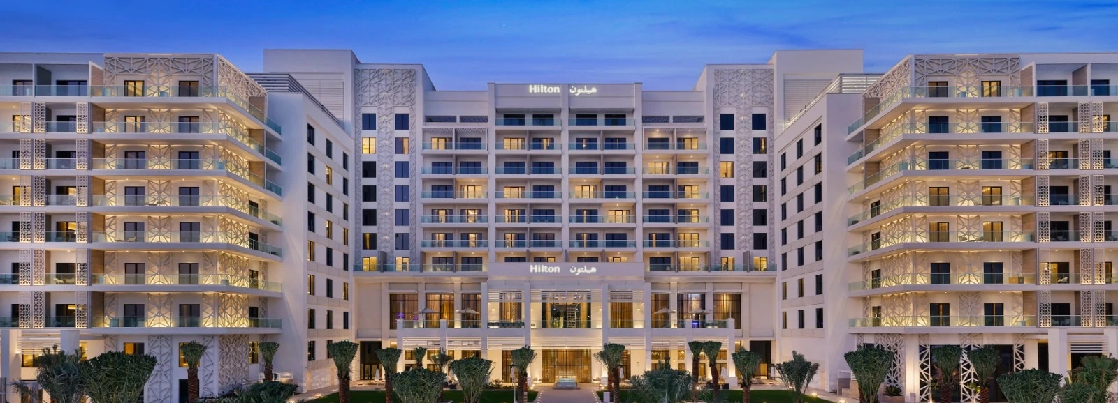 The illuminated facade of Hilton Abu Dhabi Yas Island at dusk
